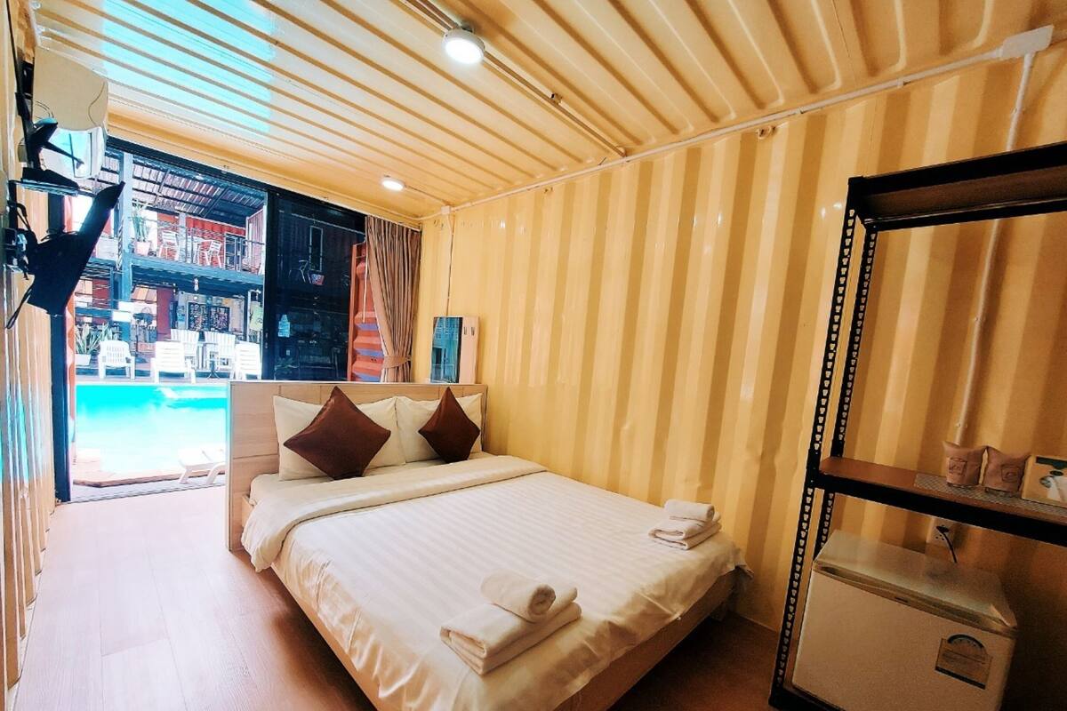 Habitación de hotel con cama, espejo y vistas al área de la piscina.
