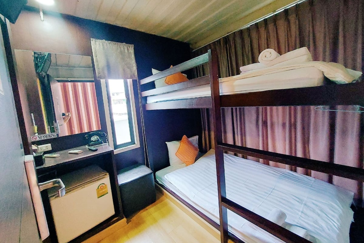 Habitación con literas, un escritorio, un espejo y una ventana con cortinas.
