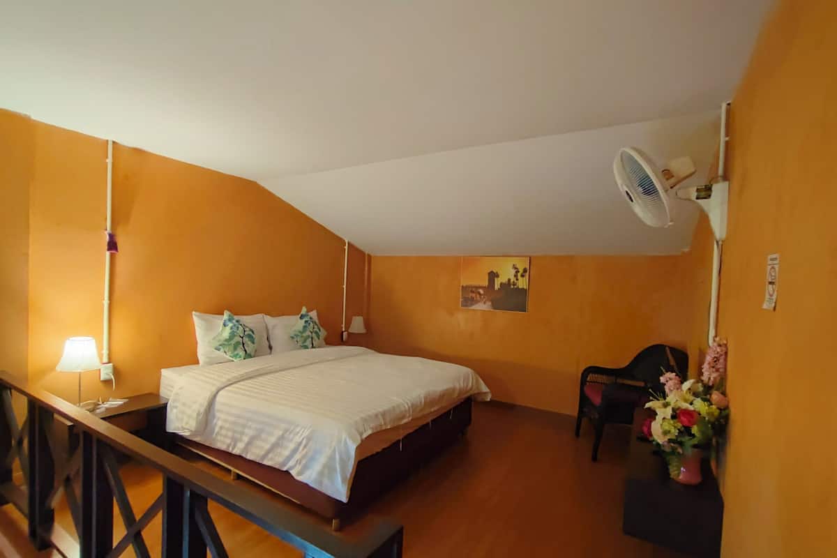 Un dormitorio con cama, escritorio, silla, ventilador y aire acondicionado instalado en la pared.