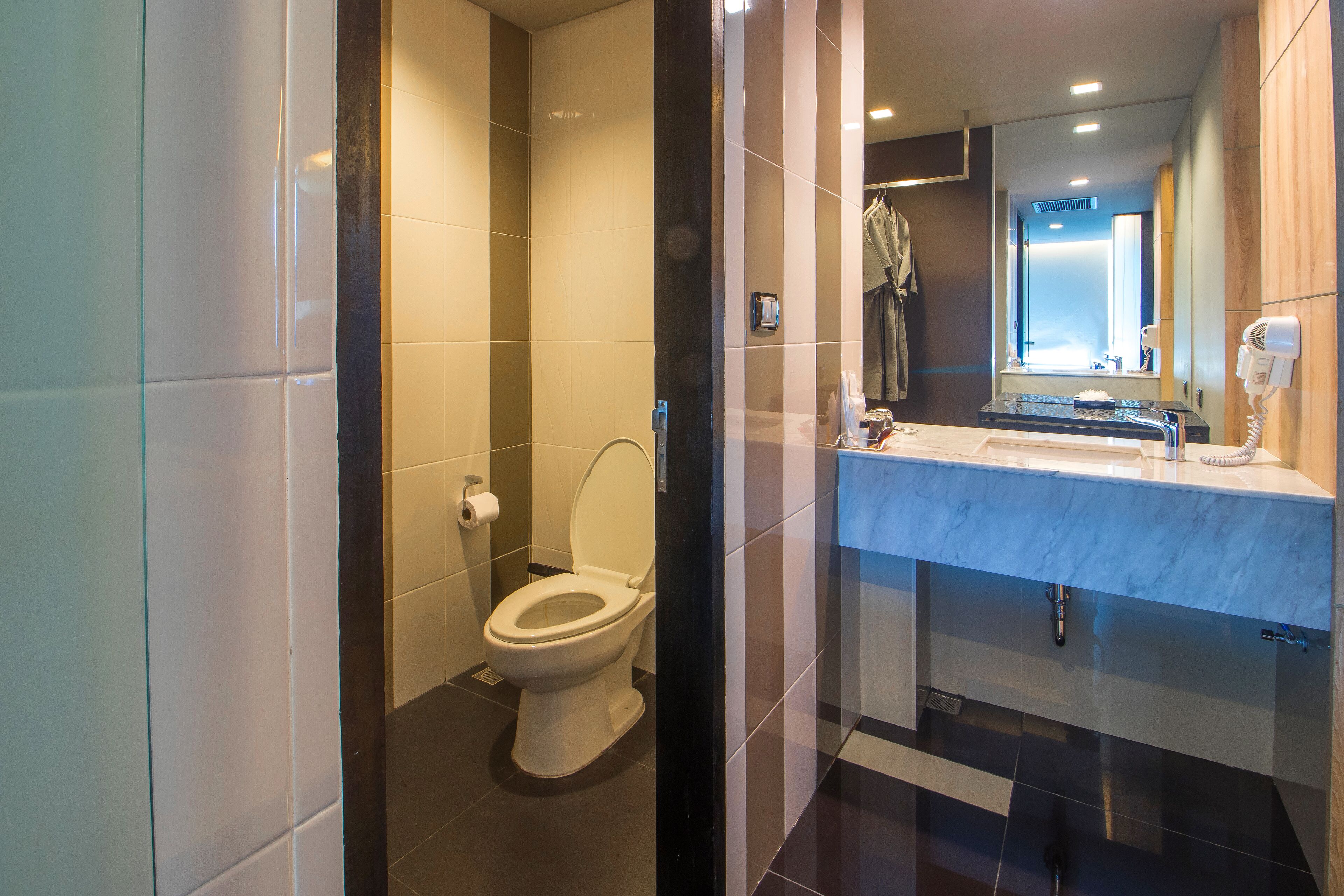 A modern bathroom with a toilet, sink, and mirror.