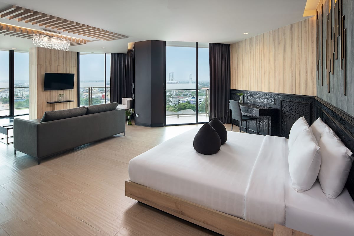 Une chambre d’hôtel moderne avec un grand lit, un canapé, une télévision et une vue sur la ville.