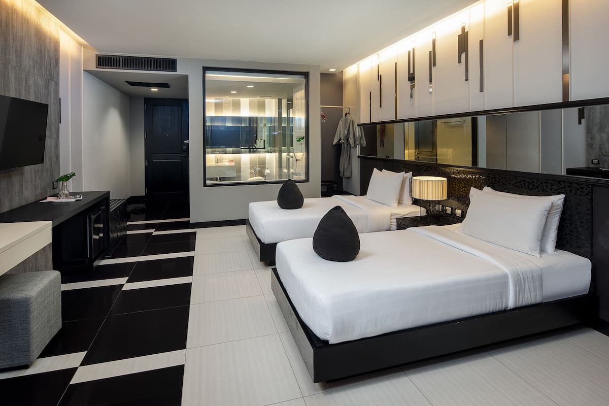 Une chambre d’hôtel moderne équipée de deux lits, d’un téléviseur à écran plat, d’un bureau et d’une grande fenêtre.