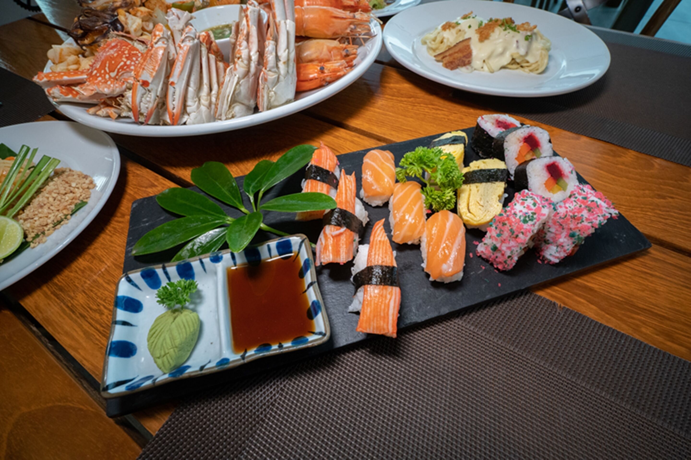 A variety of sushi and seafood dishes on a wooden table.