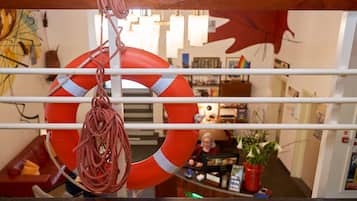A lifebuoy hanging from a railing in a room with a desk, chair, and various items on the wall.