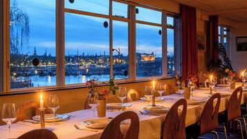 Una mesa de comedor lista para una comida, con vista a un paisaje urbano a través de amplios ventanales.