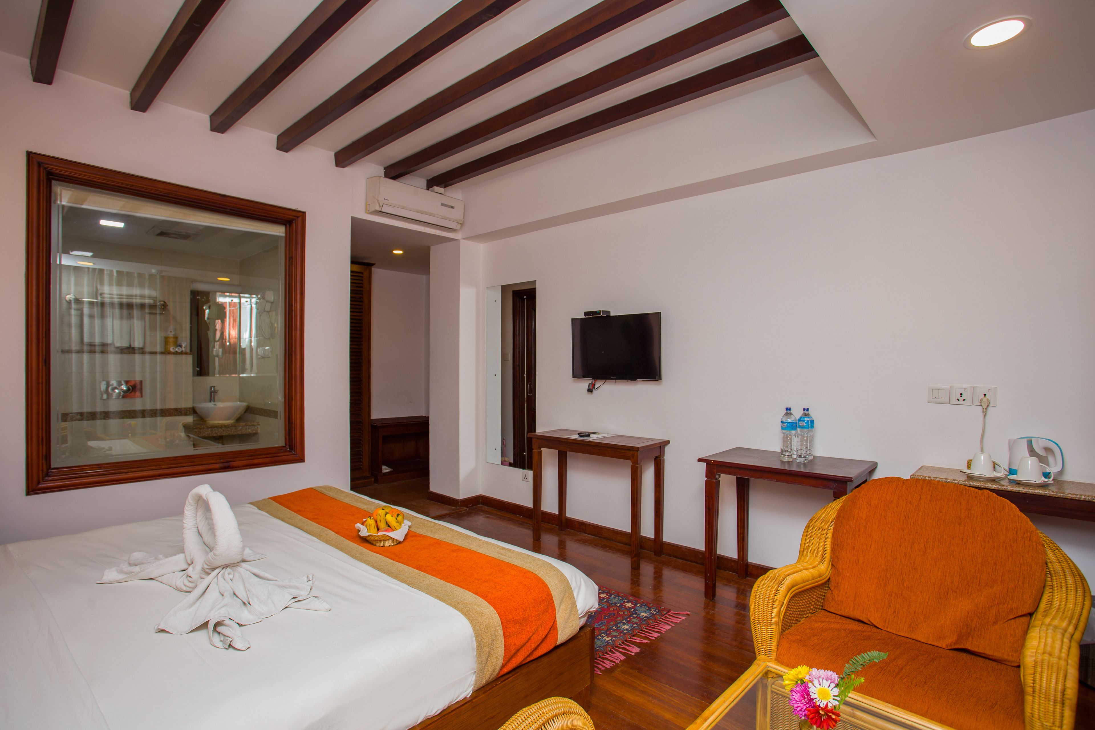Une chambre d’hôtel avec deux lits, une télévision, une petite table et une chaise en osier.