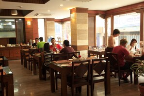 Un restaurant avec des meubles en bois et une cuisine visible au fond de la salle.