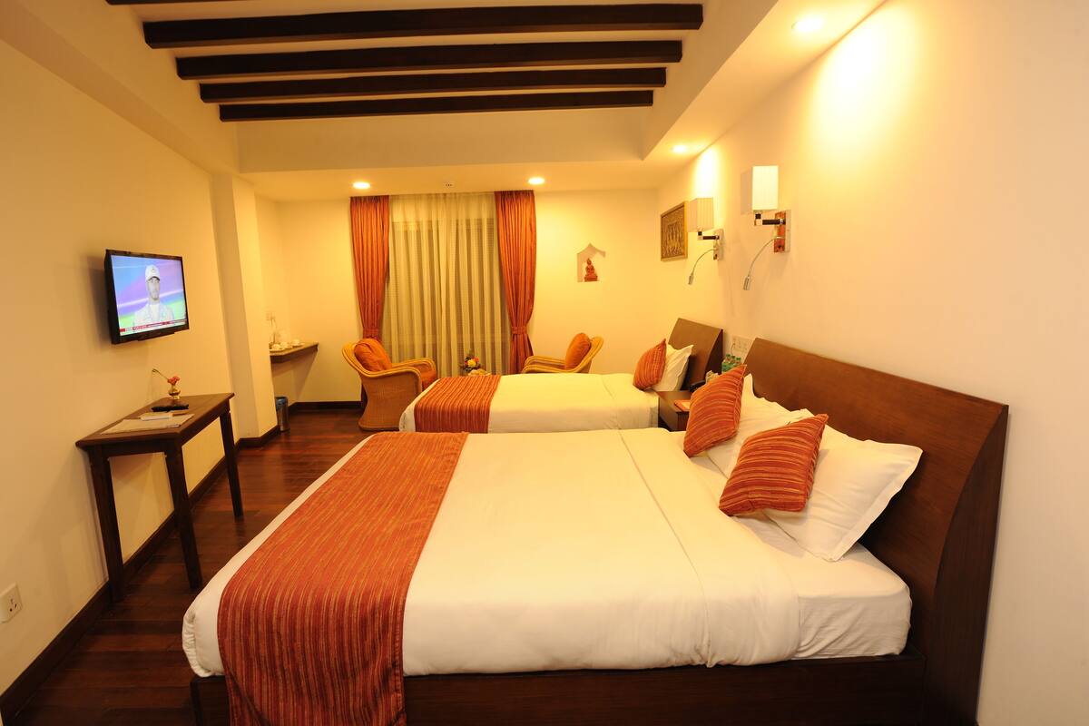 Habitación de hotel con dos camas, un televisor, un escritorio y una silla.