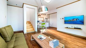 A modern living room with a sofa, a coffee table, and a TV mounted on the wall.