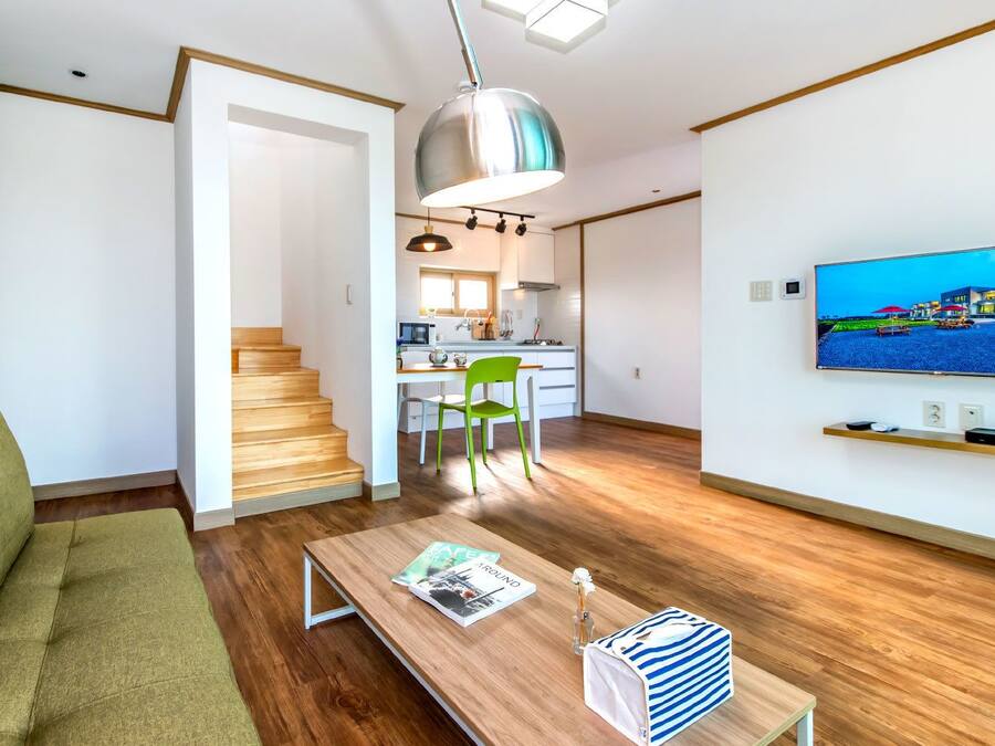 A modern living room with a sofa, a coffee table, and a TV mounted on the wall.