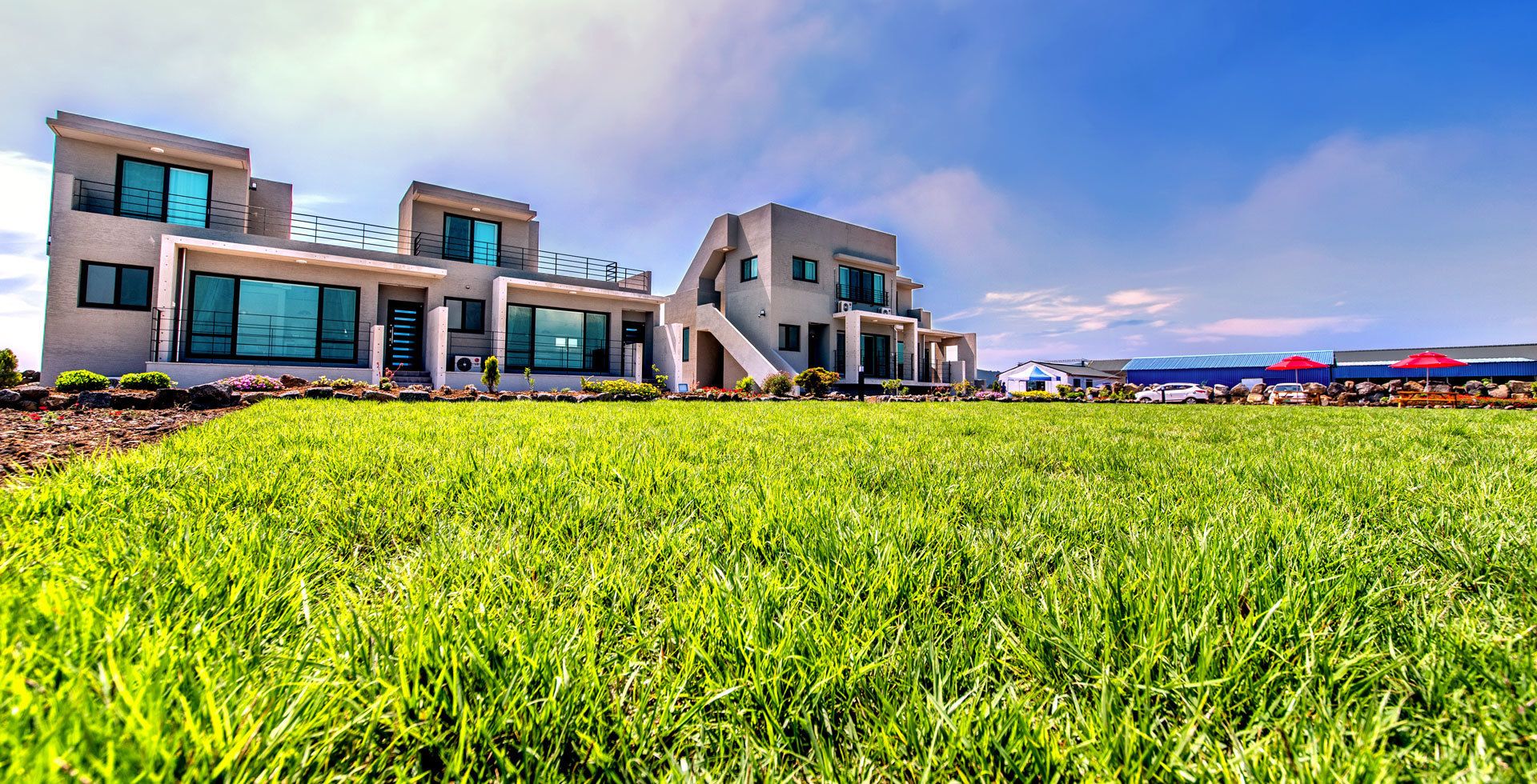 A modern multi-story building with large windows and a flat roof, surrounded by a well-maintained grassy area.
