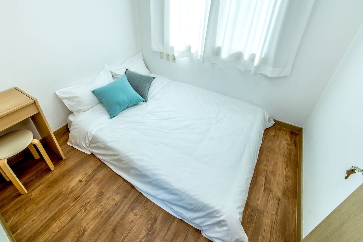 A bedroom with a bed, a desk, and a chair.