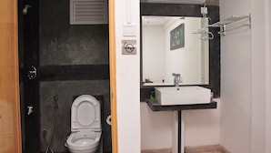 A bathroom with a toilet, a sink, a mirror, and a shower.