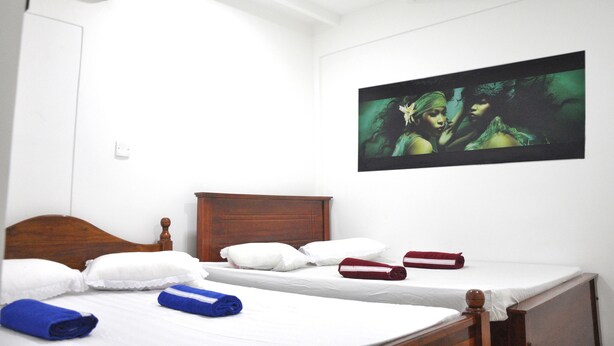 A hotel room with a wooden bed, white linens, and a large painting on the wall.