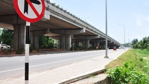 A road with a no left turn sign, an overpass, and a cyclist.
