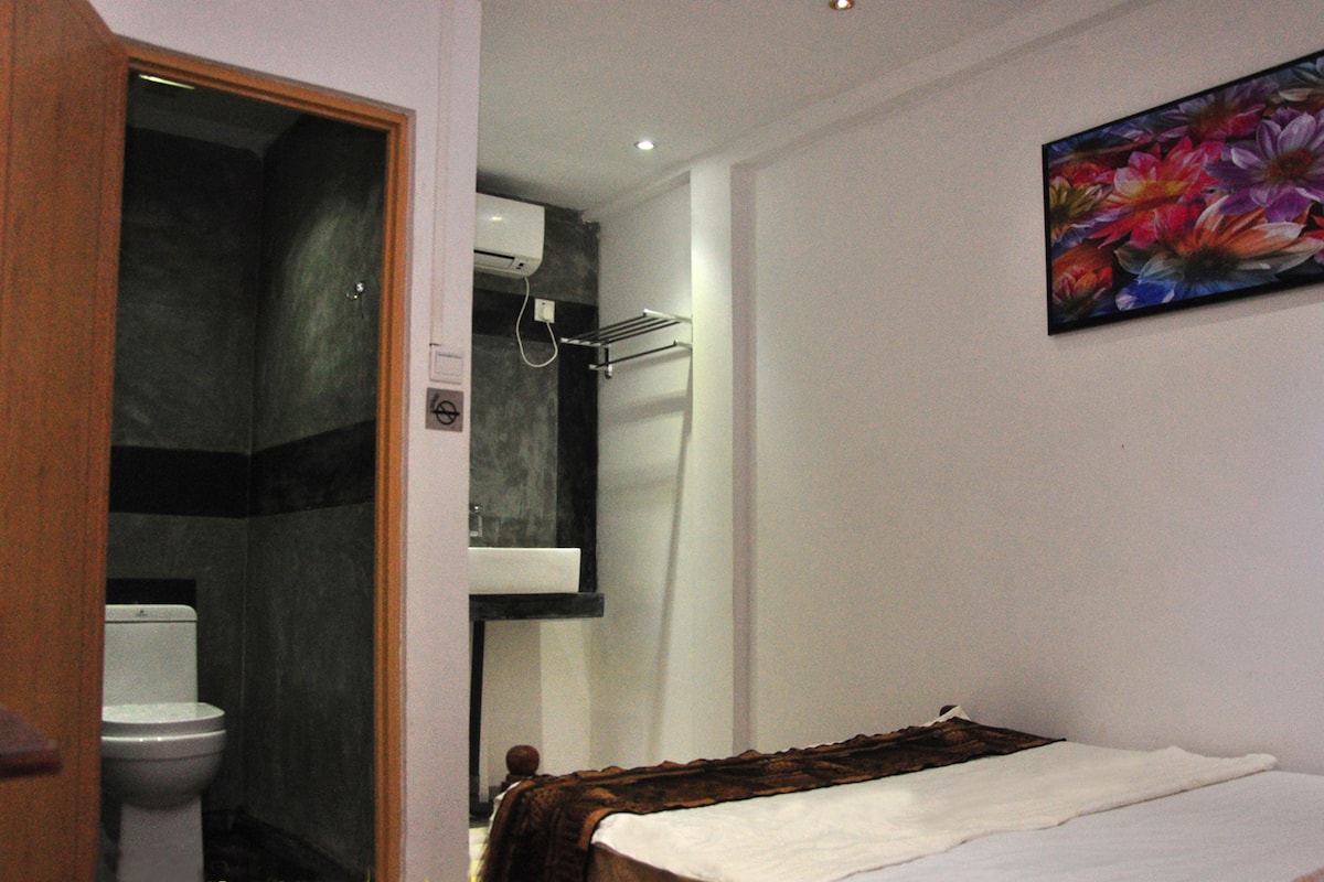 Un baño con inodoro, ducha y una cama con manta.