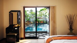 A hotel room with a bed, a desk, a piano, and a view of an outdoor swimming pool and patio area. - Samui Sun Villa (Koh Samui)
