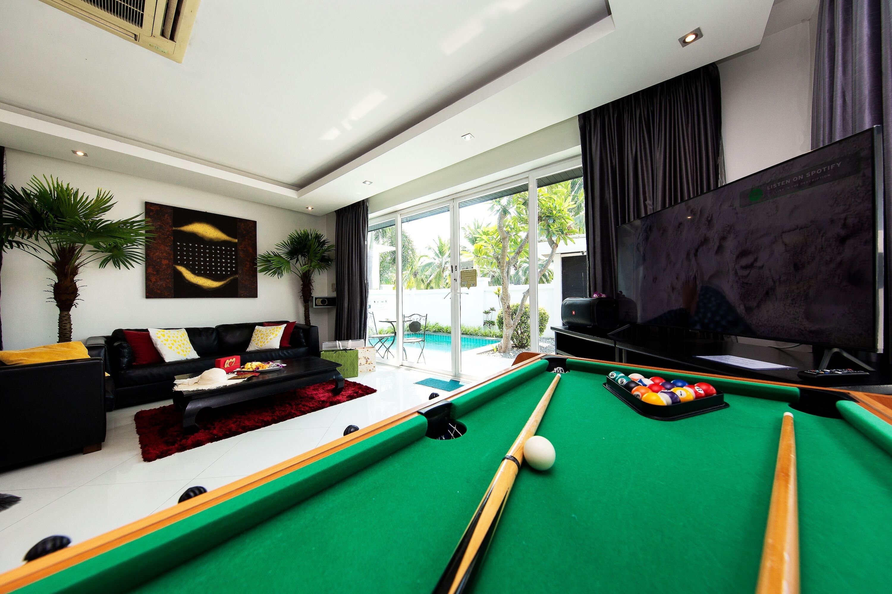 A modern living room with a pool table, a sofa, and a television.