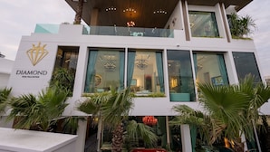 Un edificio moderno con un llamativo letrero que dice "DIAMOND", ventanas grandes y balcones con plantas.