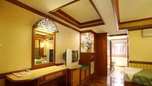 A room with wooden paneling, a desk with a computer, a television, and a chair. - Highway Hotel (Chiang Mai)