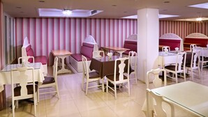 A dining area with striped wallpaper, cushioned seating, and white tables and chairs. - Highway Hotel (Chiang Mai)
