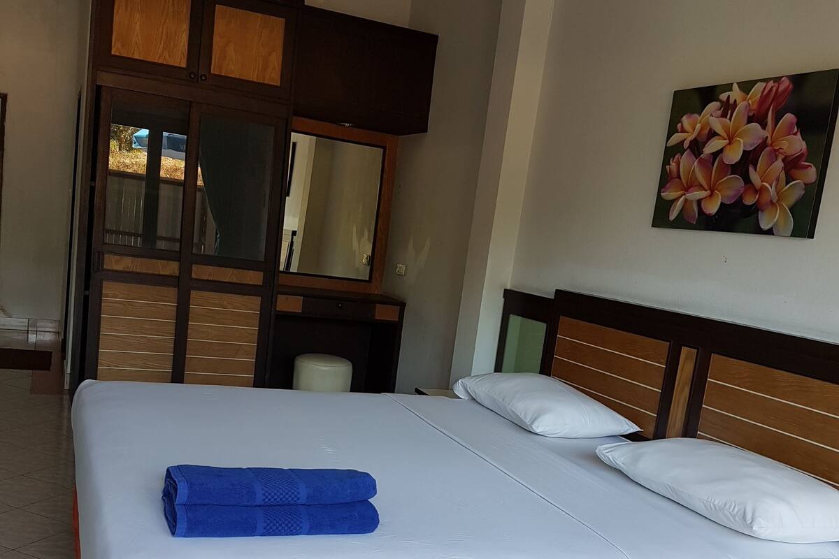 Una habitación de hotel con una cama grande, un cabecero de madera, un espejo y un cuadro de flores en la pared.