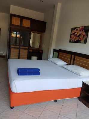 A hotel room with a large bed, a wooden headboard, a mirror, and a painting of flowers on the wall.