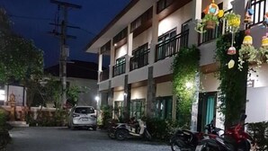A multi-story building with balconies, a gravel driveway, and parked motorcycles. - MM House Samui (Koh Samui)
