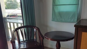A room with a wooden chair and a small round table, a window with curtains, and a green wall. - MM House Samui (Koh Samui)