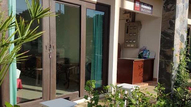 A hotel entrance with a reception desk, a signboard, and a glass door. - MM House Samui (Koh Samui)
