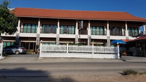 A two-story building with a red-tiled roof, multiple balconies, and a white picket fence in front. - MM House Samui (Koh Samui)