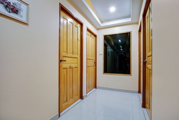 A hallway with wooden doors, a framed picture on the wall, and a large window. -  Patumnak Beach Guesthouse (Pattaya)