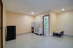 Una habitación con kitchenette, una pequeña mesa y una puerta con diseño decorativo.