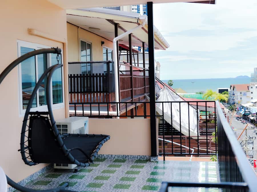 Un balcón con vistas al mar, una silla y suelo de baldosas.
