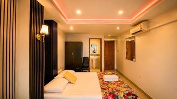 A hotel room with a bed, a wardrobe, a mirror, and an air conditioning unit.