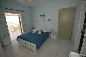 Ein Schlafzimmer mit Bett, Nachttisch, Tür und Blick ins Freie.