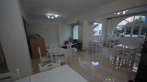 A spacious room with white furniture, a large window, and a door leading to another area. - Ocean View (Naxos)
