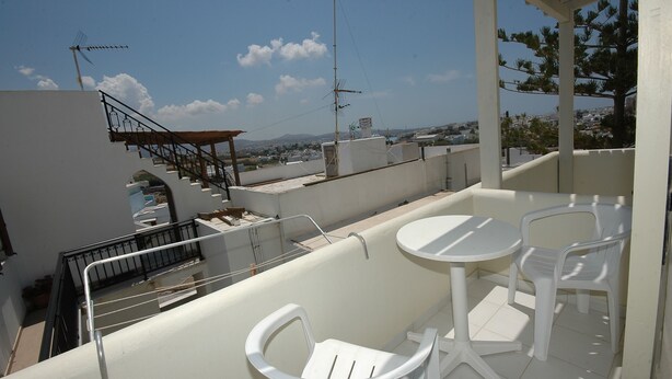A rooftop terrace with a small table and two chairs, a staircase, and a view of the cityscape. - Ocean View (Naxos)