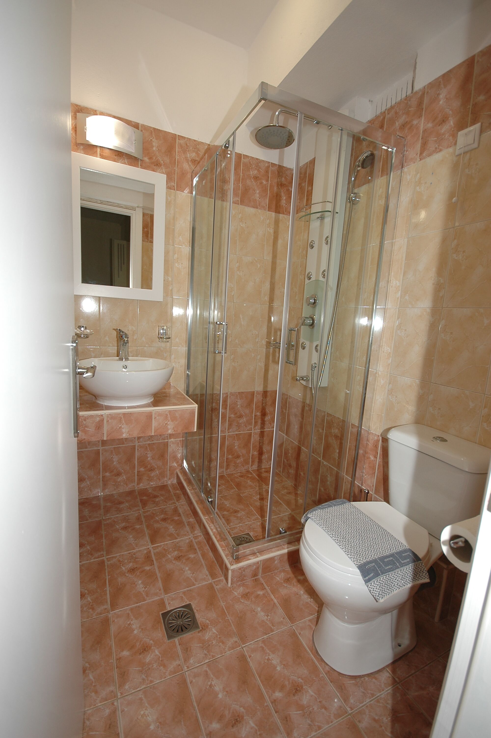 A bathroom with a glass-enclosed shower, a sink, and a toilet.