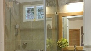 A modern bathroom with a glass-enclosed shower, a white toilet, a sink with a mirror, and a small shelf with a towel. - Harvest Fresh Farms (Uthamapalayam)