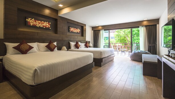 Une chambre d’hôtel avec deux lits, un bureau et un balcon donnant sur un espace verdoyant.