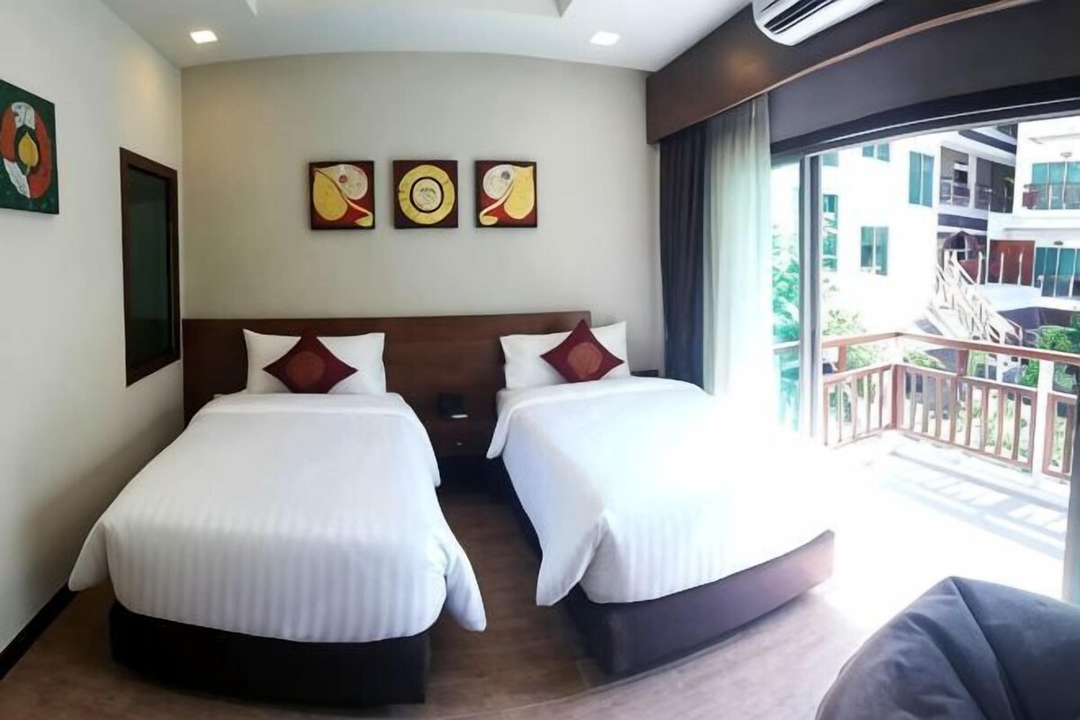 Habitación de hotel con dos camas, un balcón con barandilla y una obra de arte en la pared.