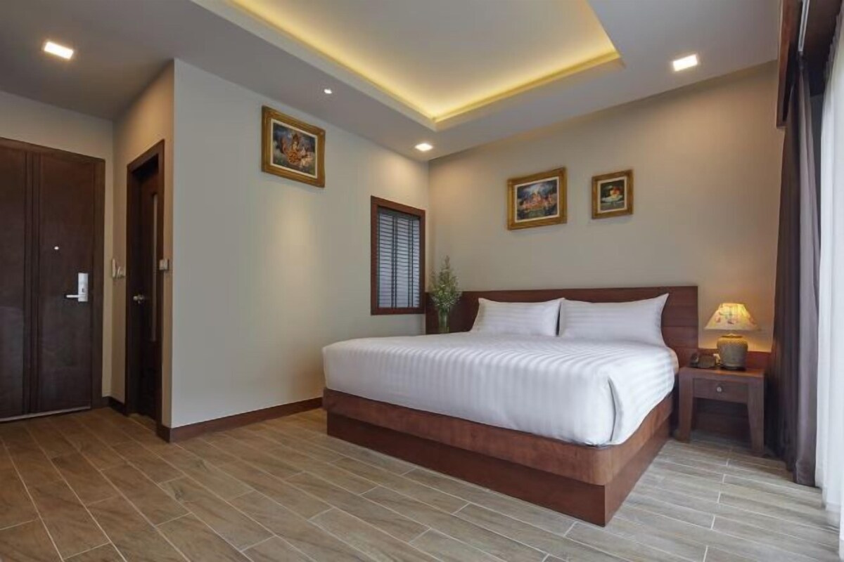 Una habitación de hotel con una cama grande, una mesita de noche y una puerta.
