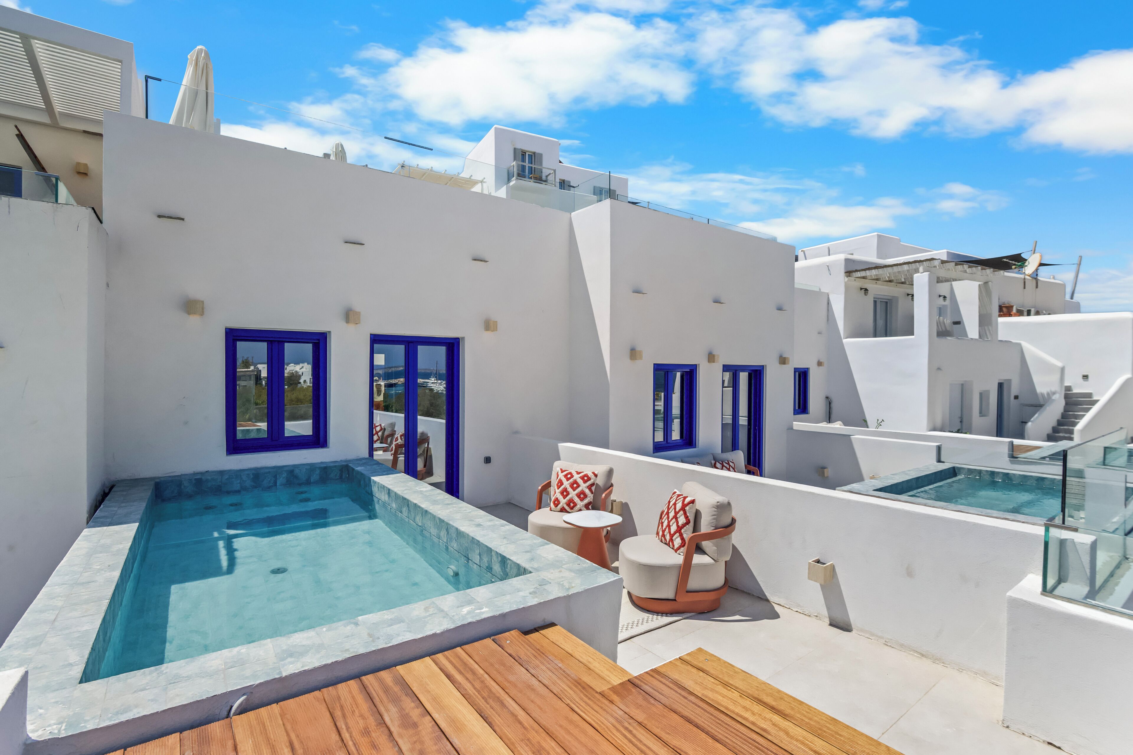Una terraza en la azotea con piscina, mobiliario exterior y una vista despejada del cielo.