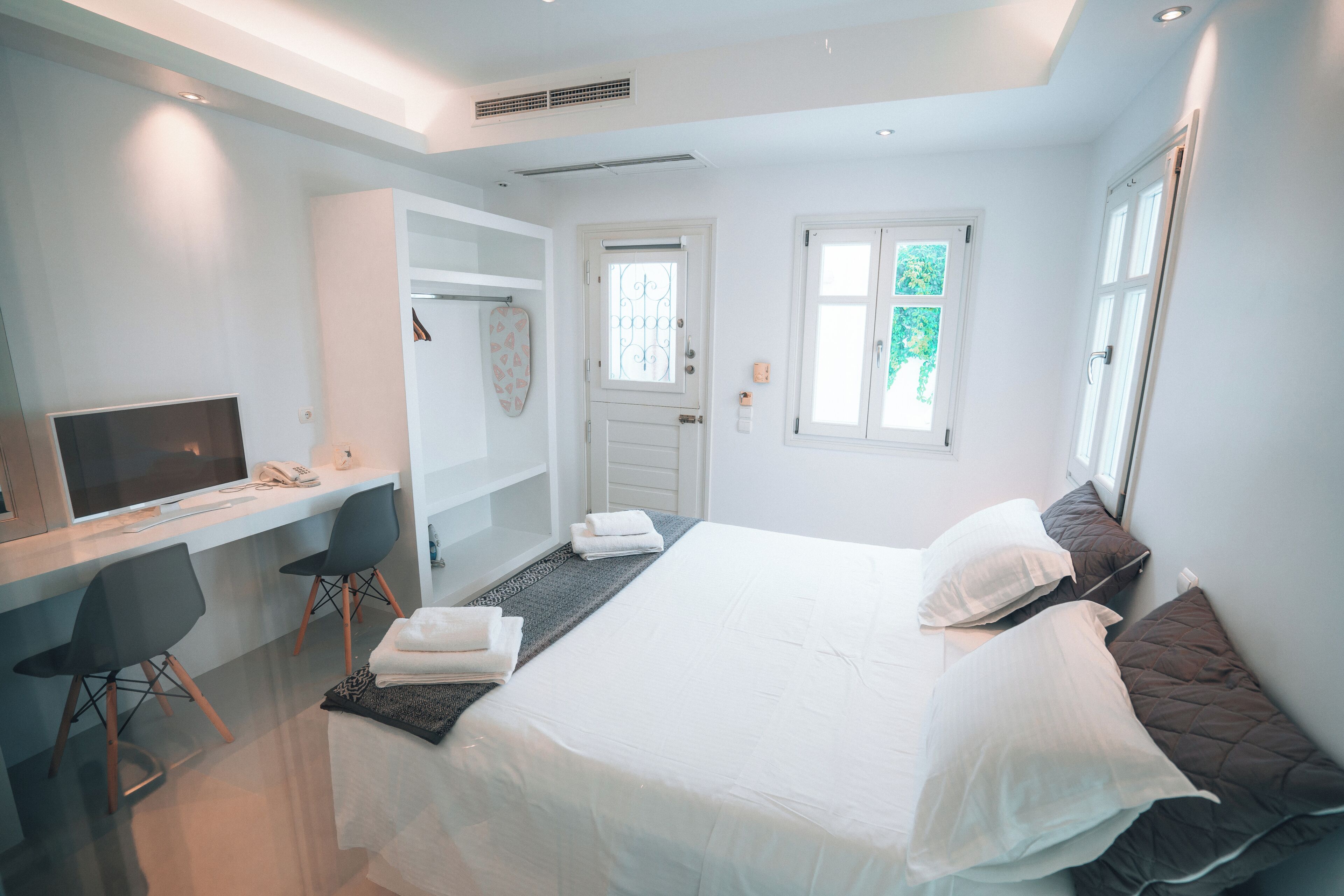 Une chambre d’hôtel moderne dotée d’un grand lit, d’un bureau avec un ordinateur et d’un coin salon avec des fauteuils.