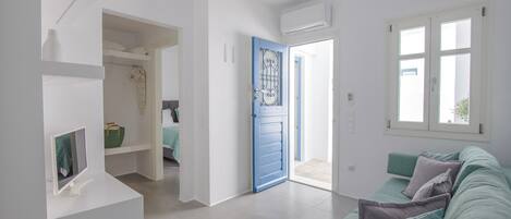 A modern living room with a teal sofa, a white console table, and a blue door leading to a bathroom.