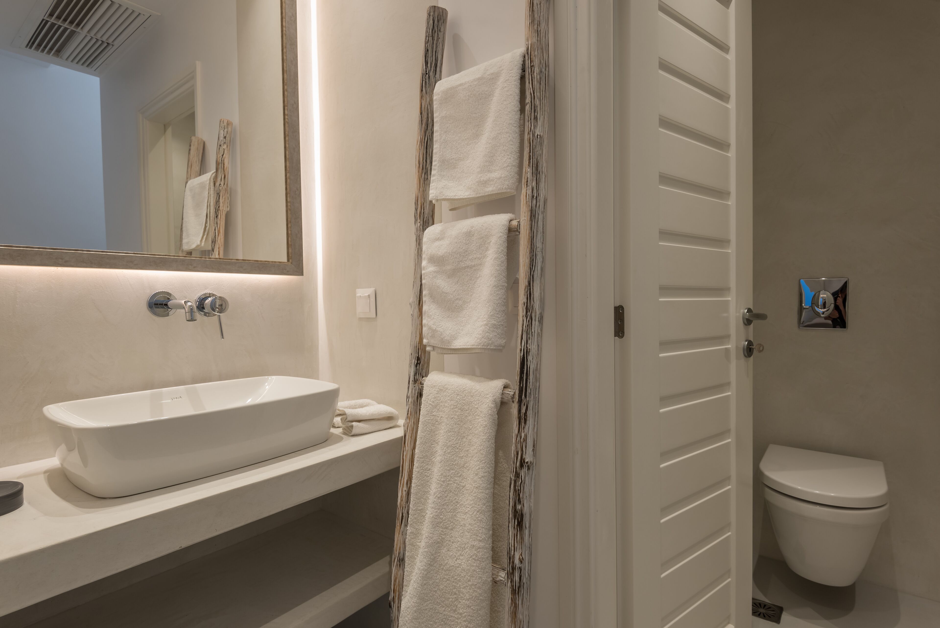 Een badkamer met een wit wastafel, spiegel en toilet.
