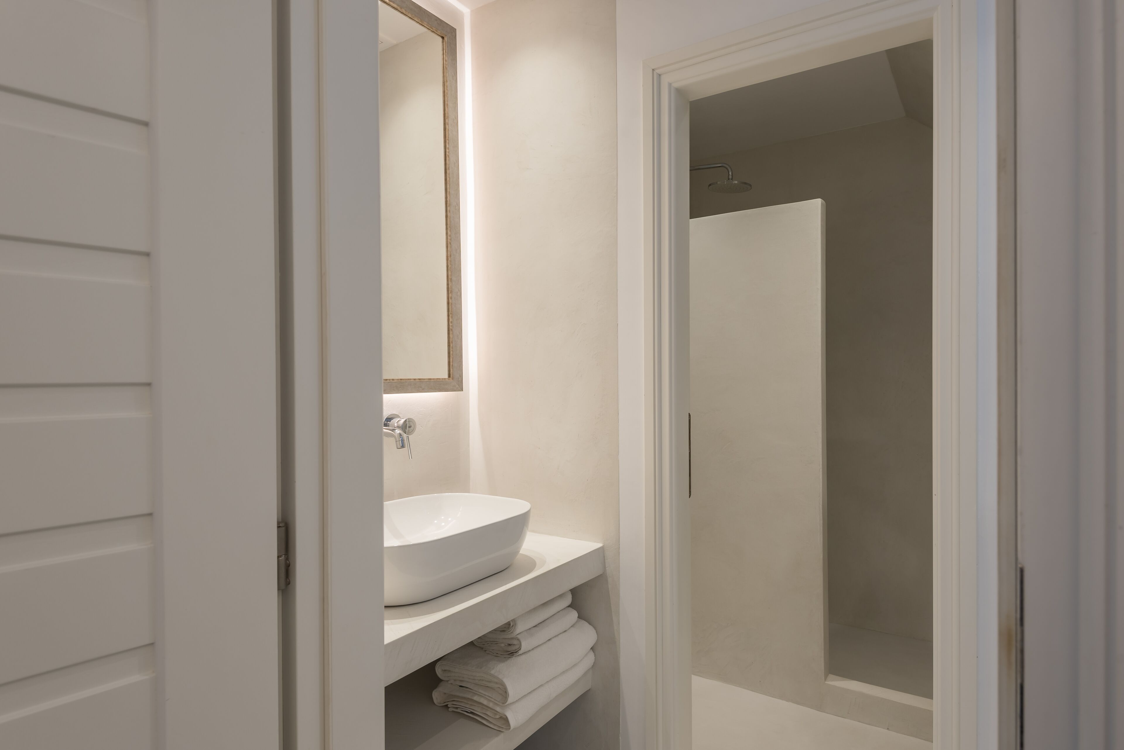 Une salle de bain avec un lavabo blanc, un miroir et une douche.