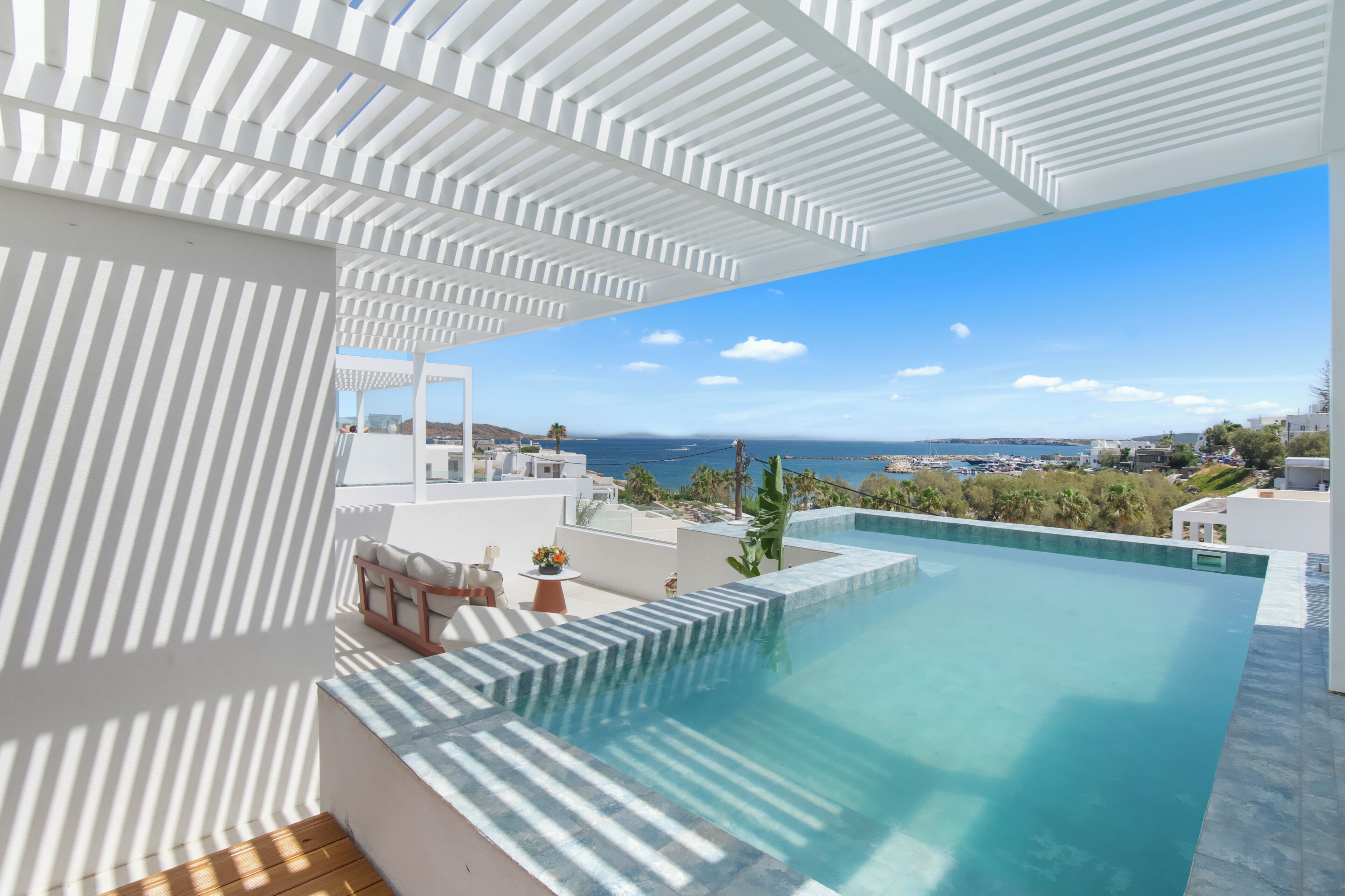 A rooftop infinity pool with a clear view of the sea and a white architectural design.