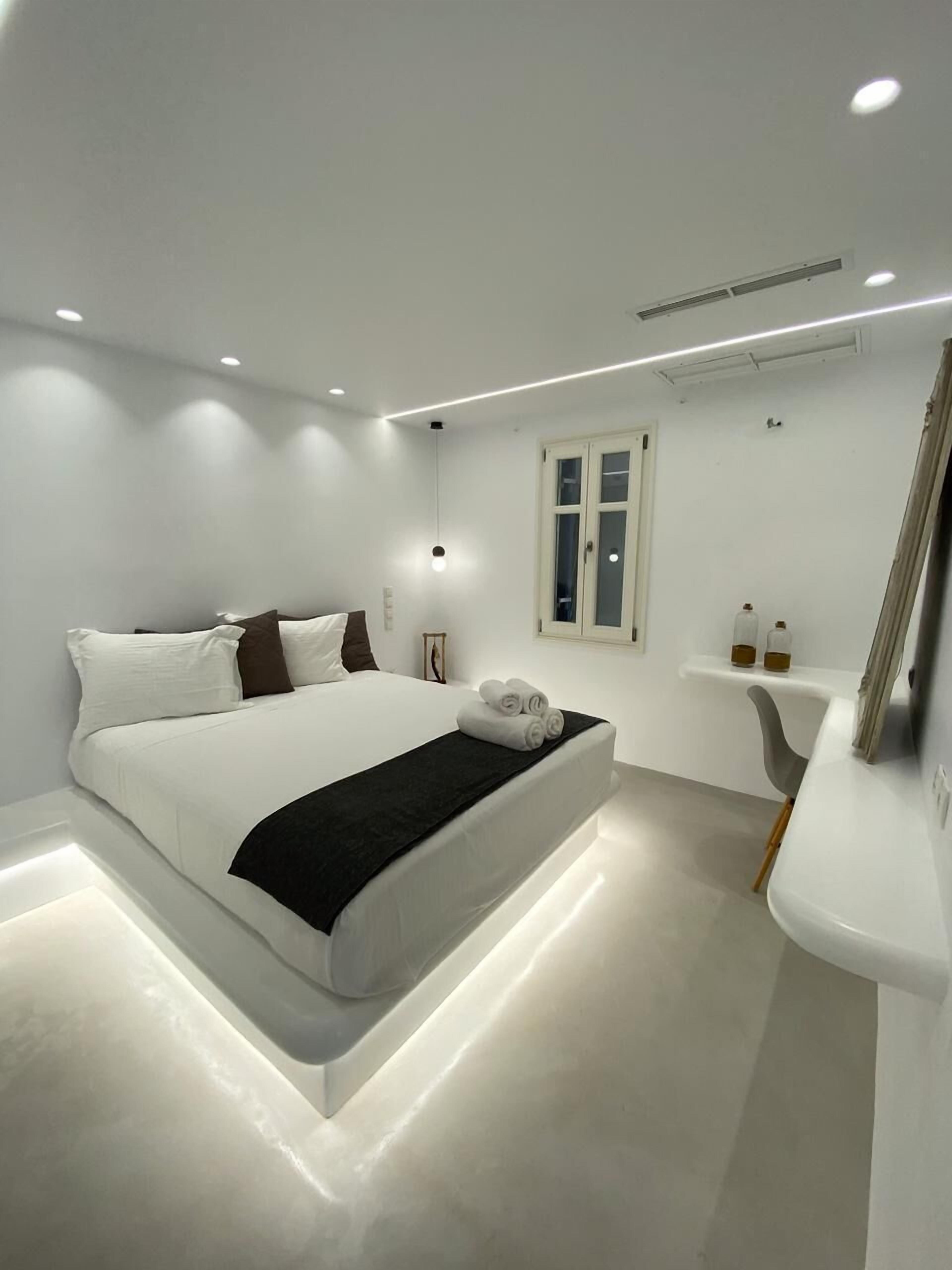 Un dormitorio moderno con cama, mesita de noche y espejo.